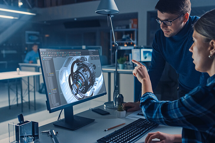 Ein Person sitzt an einem PC auf dem eine Ingenieurssoftware zu sehen ist
