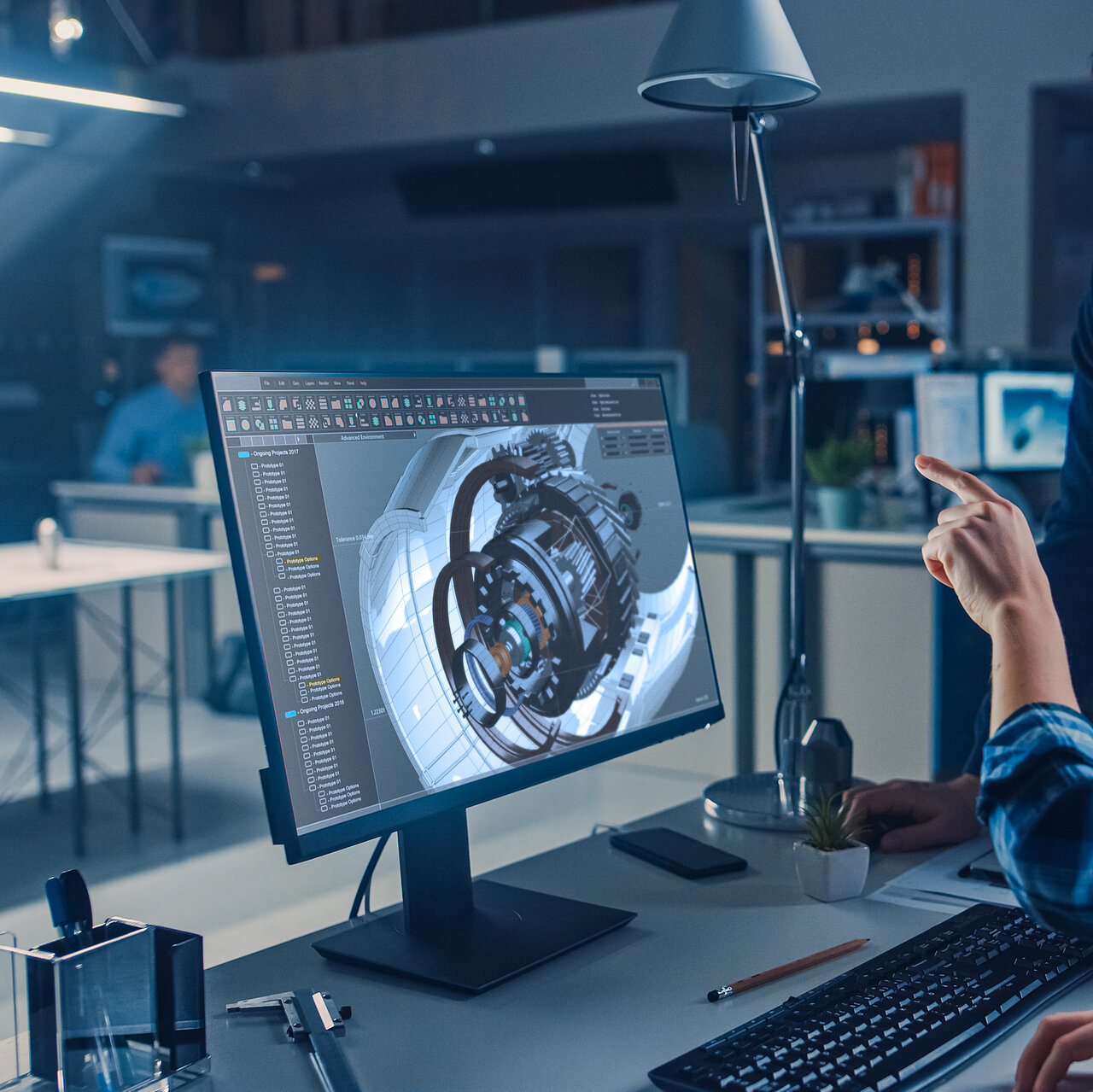 Ein Person sitzt an einem PC auf dem eine Ingenieurssoftware zu sehen ist