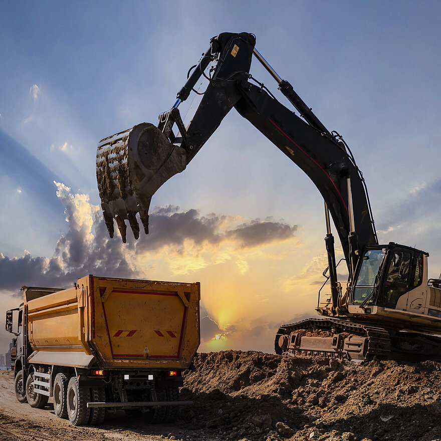 Ein großer Bagger lädt Sand in einen LKW
